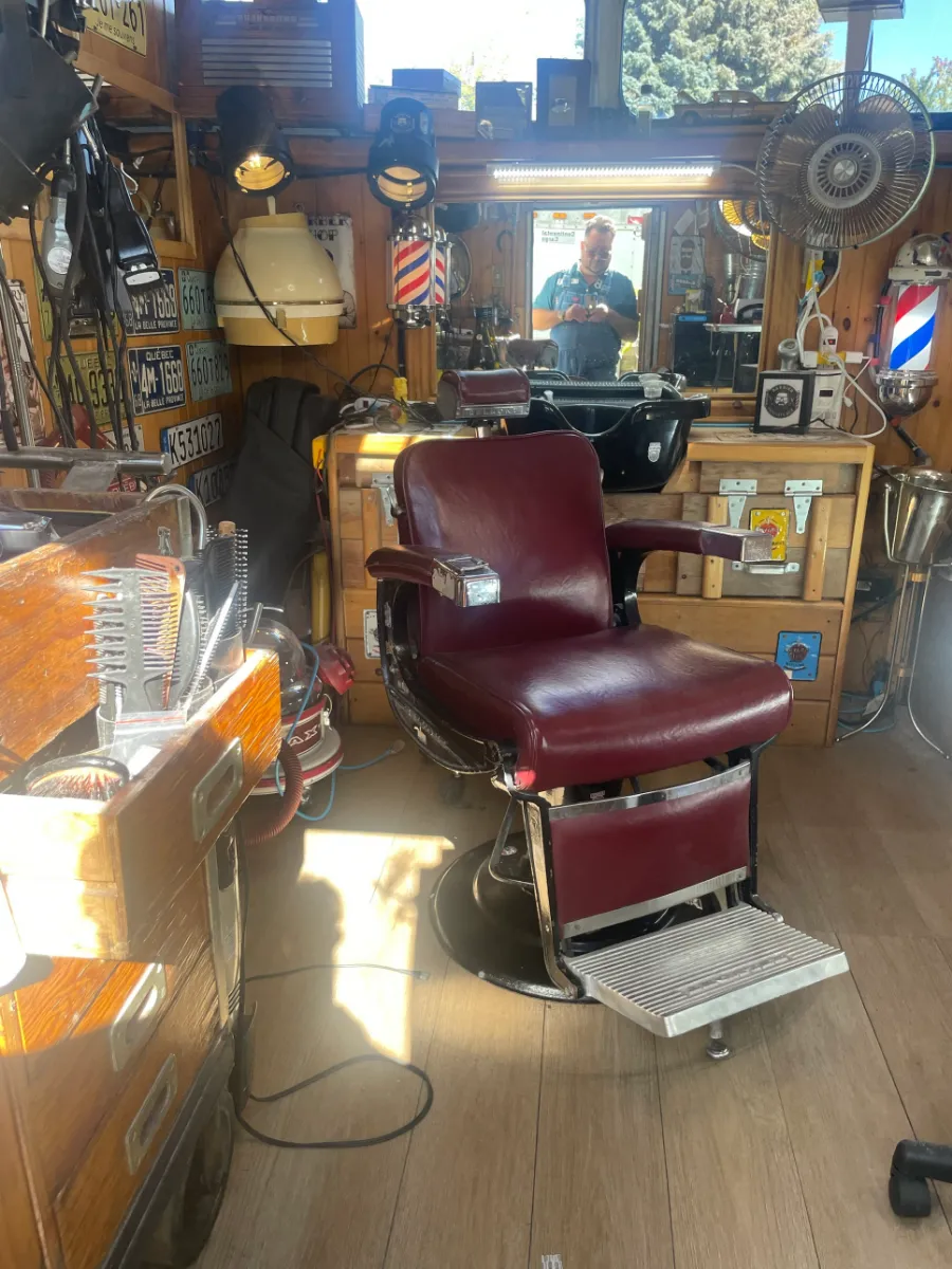 Le fauteuil de barbier Belmont en cuir bourgogne, dans le salon lambrissé de bois