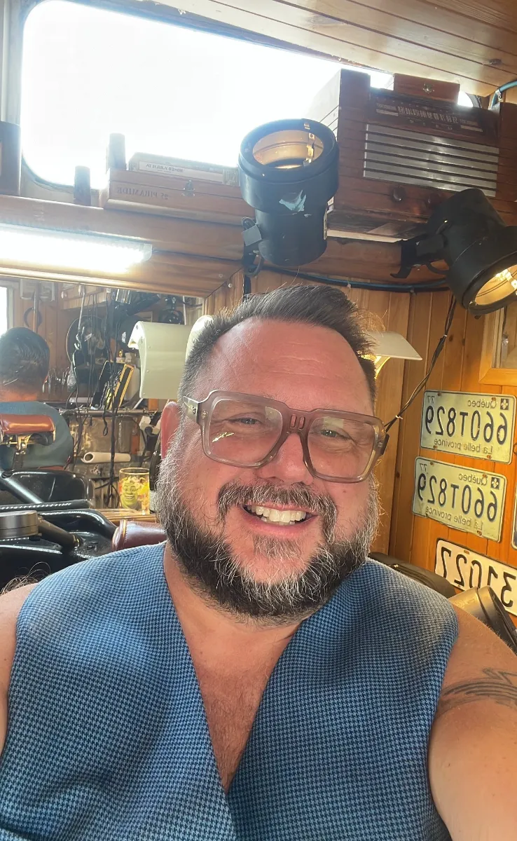 Jimmy Descôteaux, souriant, dans son salon devant les plaques du Québec